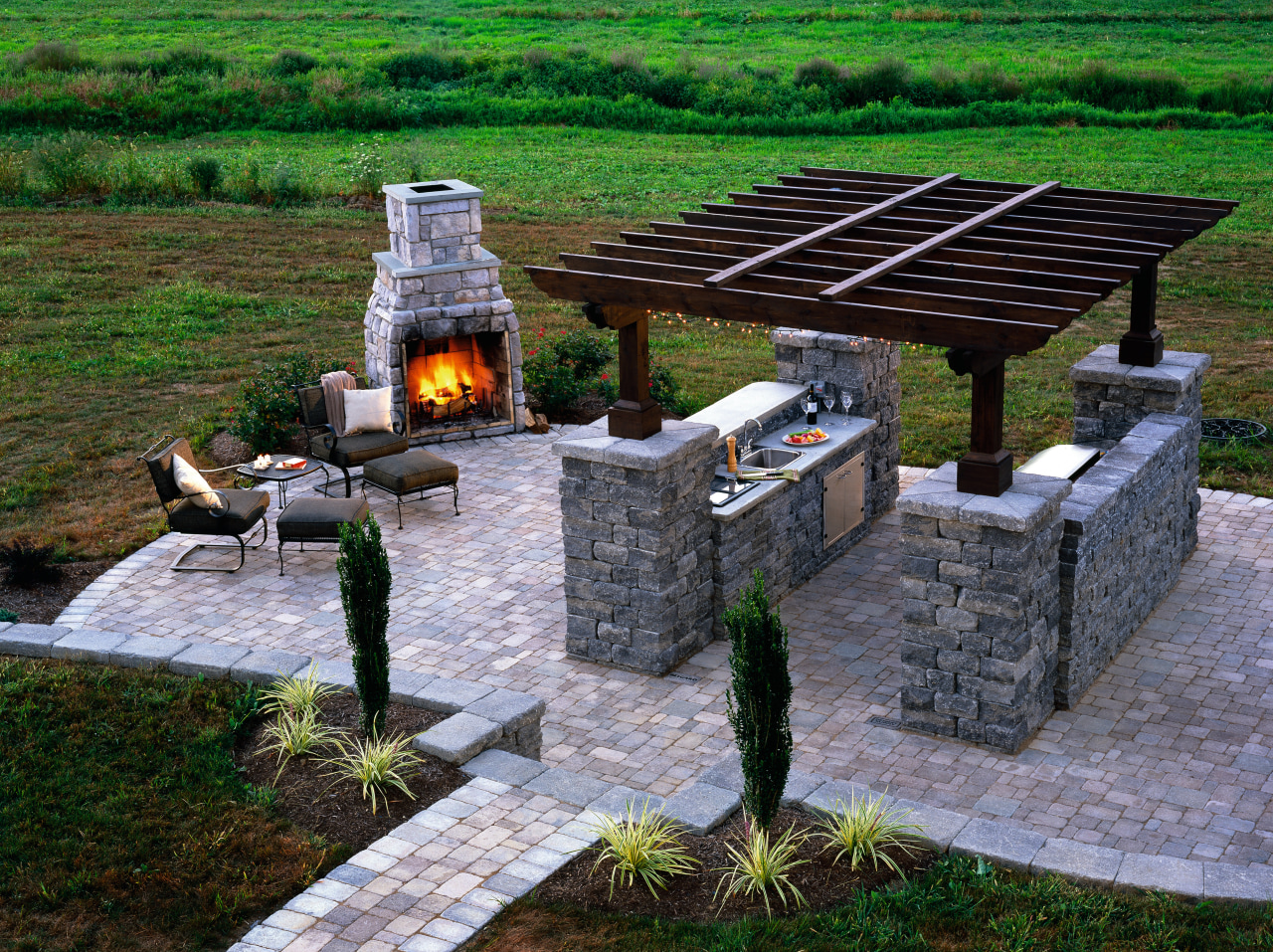 Outdoor entertainment and barbeque patio area with paved landscape, outdoor structure, green