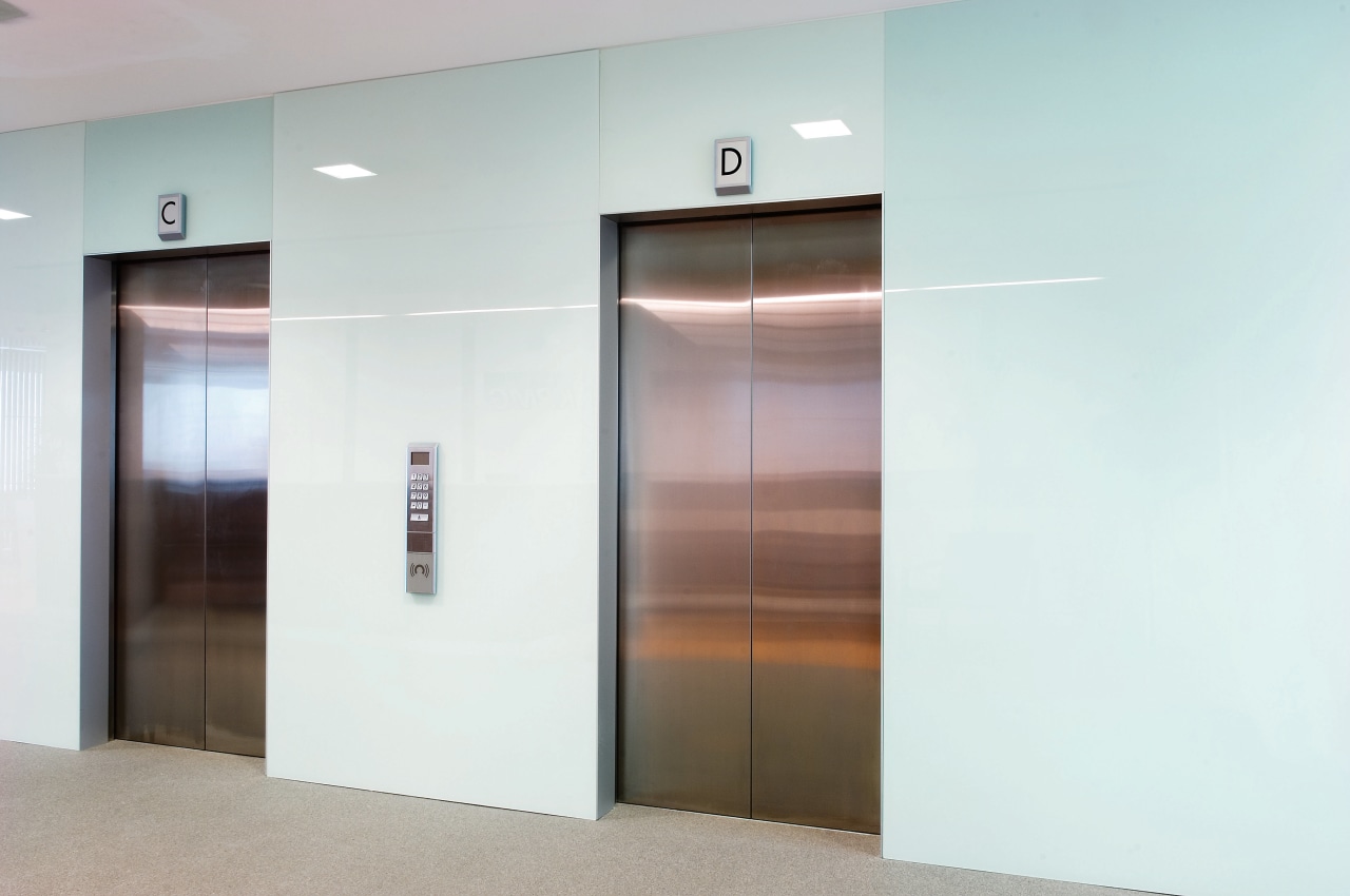 A view of the elevator lobby feauting glass door, elevator, glass, white