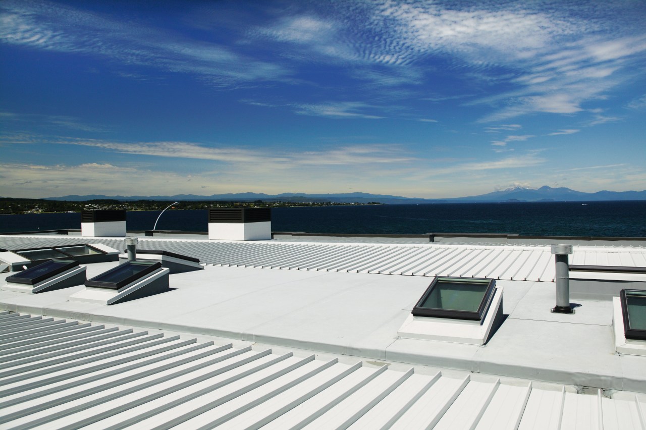 A view of a low pitched grey steel daylighting, deck, roof, sky, water, yacht, white