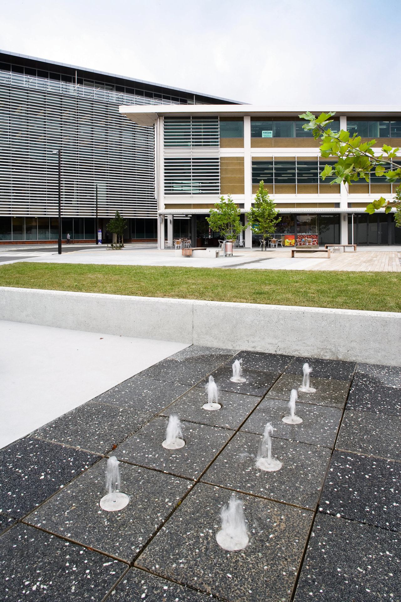 An exterior view of this building featuring metal architecture, asphalt, building, condominium, facade, house, residential area, road surface, roof, urban design, white