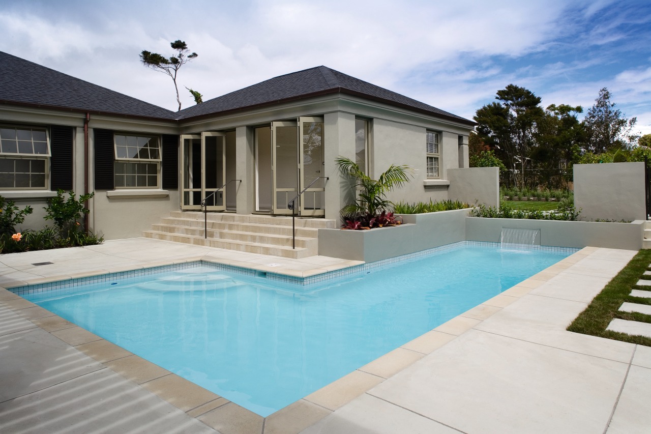 A view of a swimming pool built by backyard, estate, facade, home, house, property, real estate, residential area, swimming pool, villa, window, gray