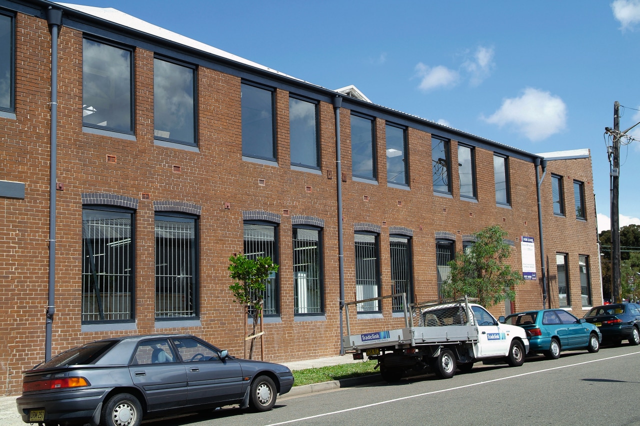 A view of this 1970s masonry warehouse with apartment, architecture, building, car, city, commercial building, condominium, corporate headquarters, downtown, facade, family car, home, house, luxury vehicle, metropolitan area, mixed use, neighbourhood, property, real estate, residential area, town, vehicle, brown