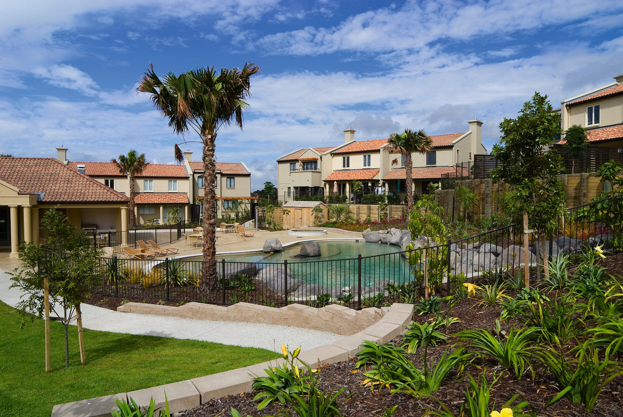 A view of the Point Ridge development. arecales, backyard, condominium, cottage, estate, hacienda, home, house, leisure, neighbourhood, palm tree, property, real estate, residential area, resort, sky, swimming pool, tree, villa, water, teal, brown