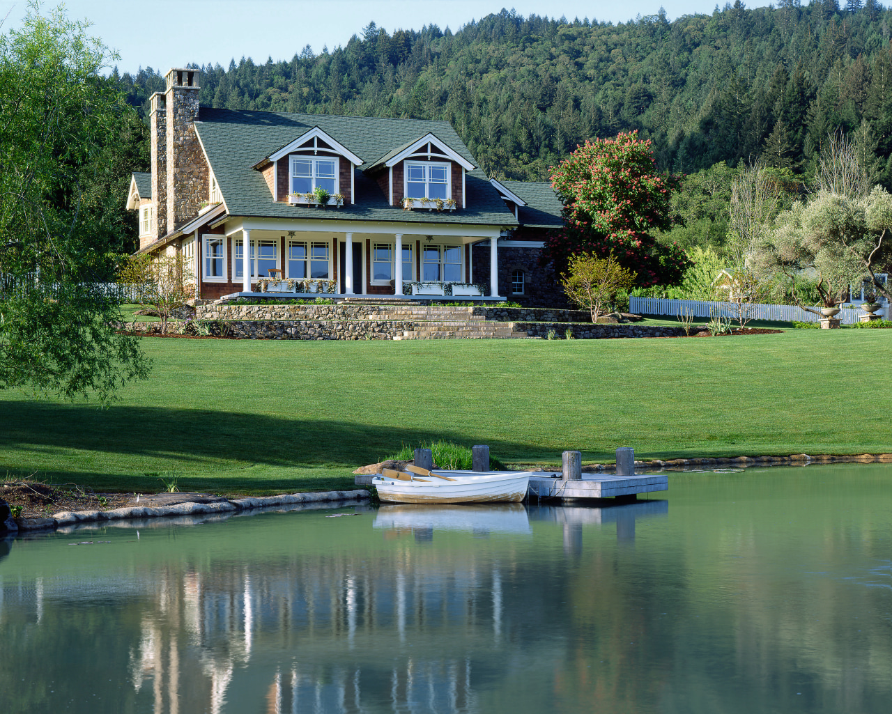 An exterior view of this traditional masonry home bank, canal, cottage, estate, farmhouse, home, house, lake, landscape, pond, property, real estate, reflection, reservoir, tree, water, waterway, green