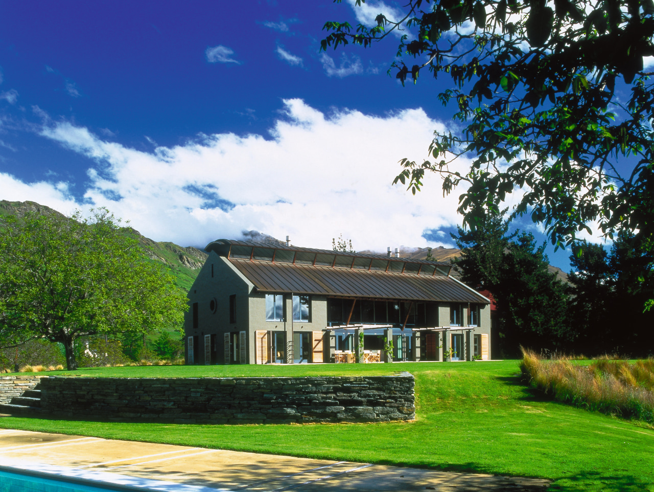 An exterior view of this rural home designed cottage, estate, facade, farm, farmhouse, grass, home, house, land lot, landscape, lawn, plantation, property, real estate, roof, sky, tree, villa