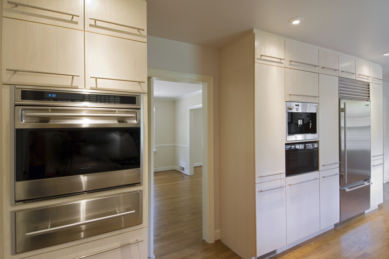 A view of this minimalist clean lined kitchen cabinetry, countertop, home appliance, kitchen, kitchen appliance, kitchen stove, major appliance, microwave oven, oven, refrigerator, room, gray, brown