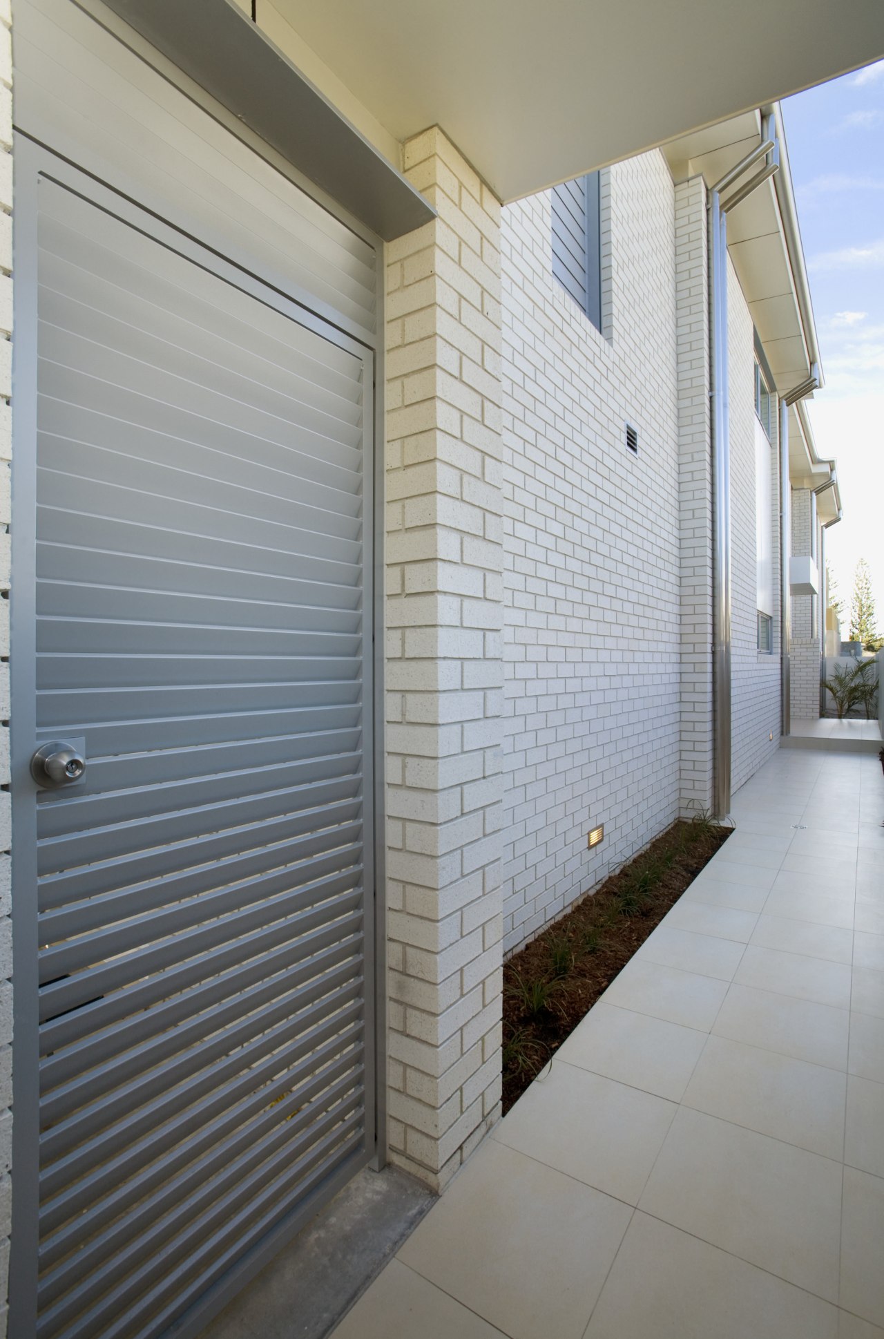 Side view of brick house, alongside steel gate apartment, architecture, daylighting, door, facade, home, house, interior design, property, real estate, wall, window, gray