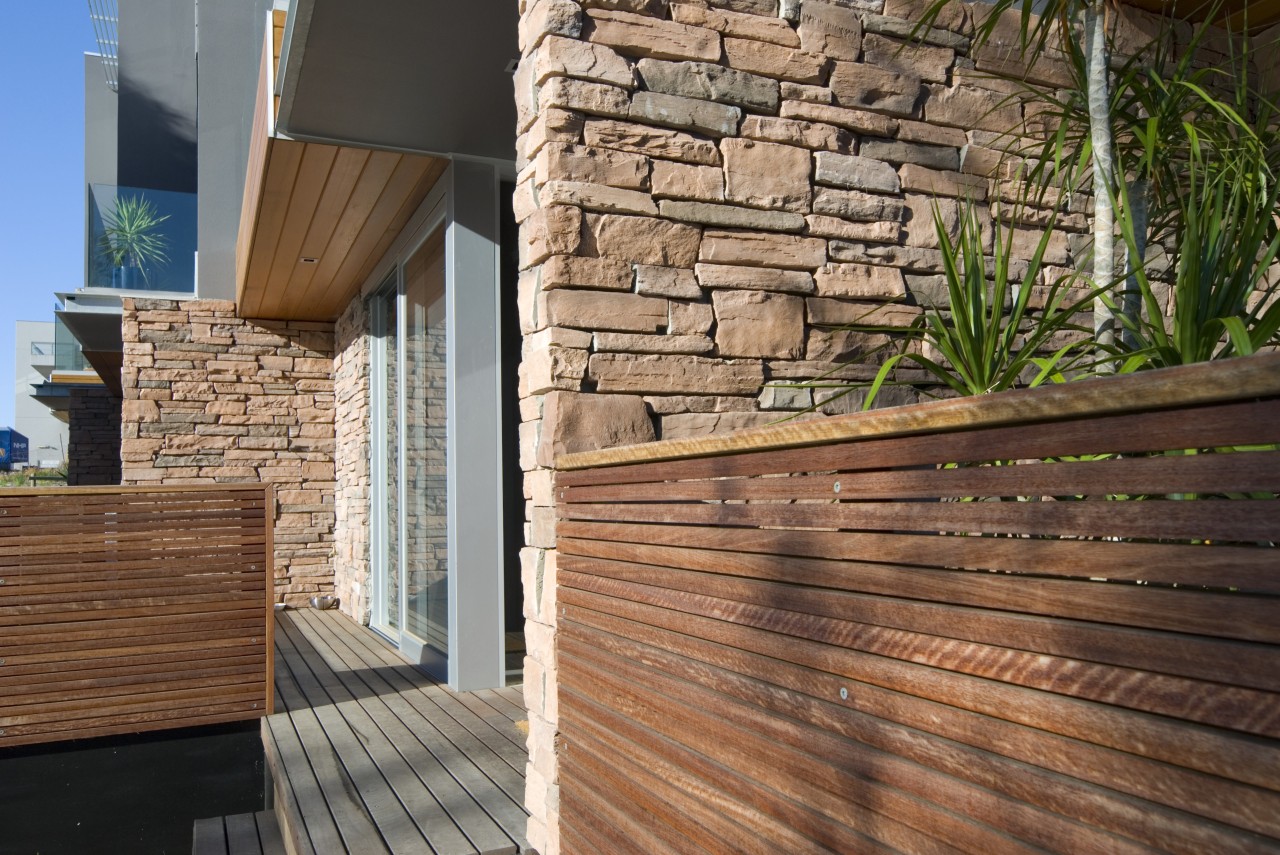 A solid stone wall with wood fencing architecture, deck, facade, hardwood, home, house, lumber, outdoor structure, real estate, siding, wall, wood, wood flooring, wood stain, brown