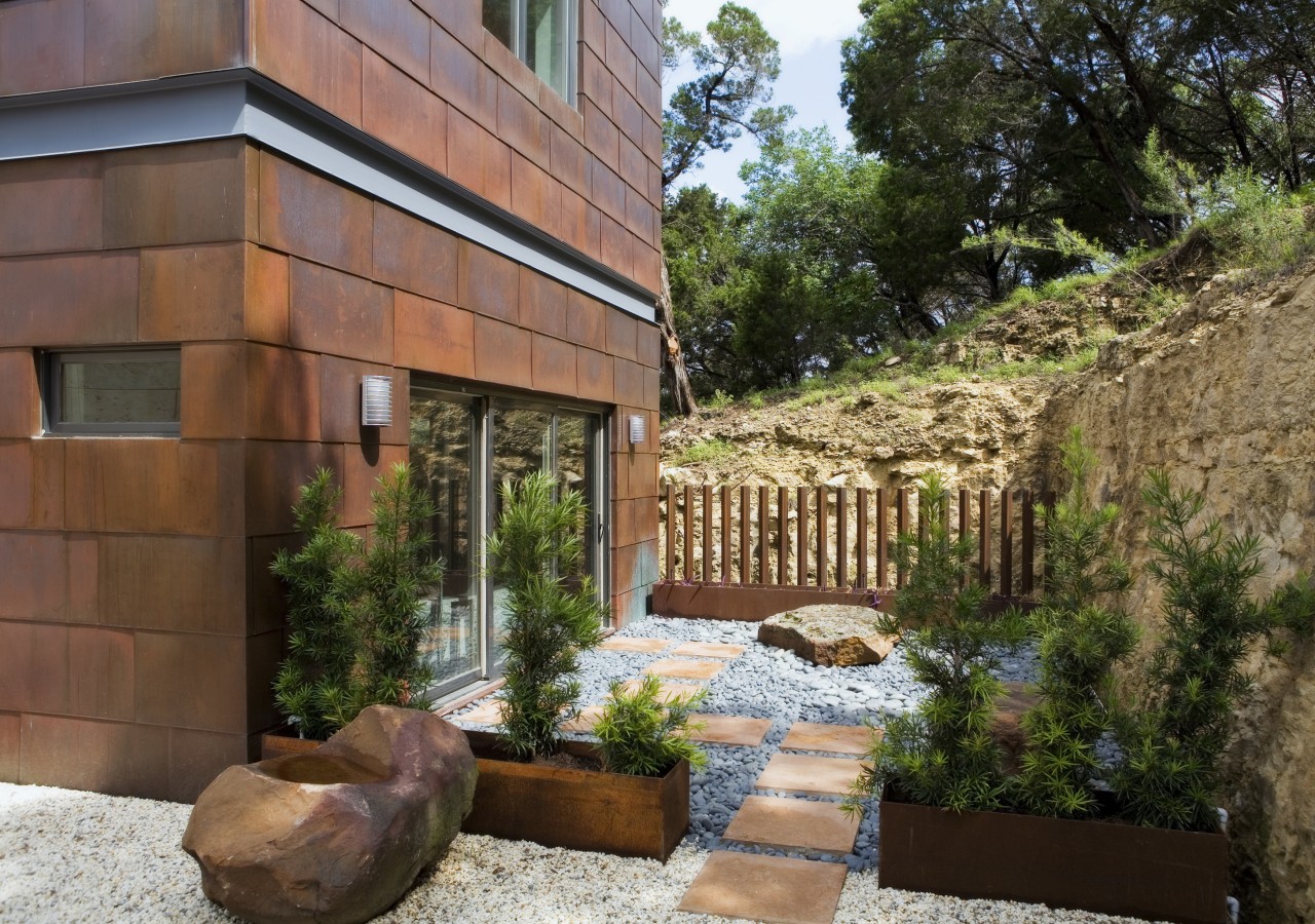 Exerior view of bathroom featuring sliding doors, pavers, backyard, courtyard, estate, home, house, landscape, landscaping, outdoor structure, property, real estate, yard, brown
