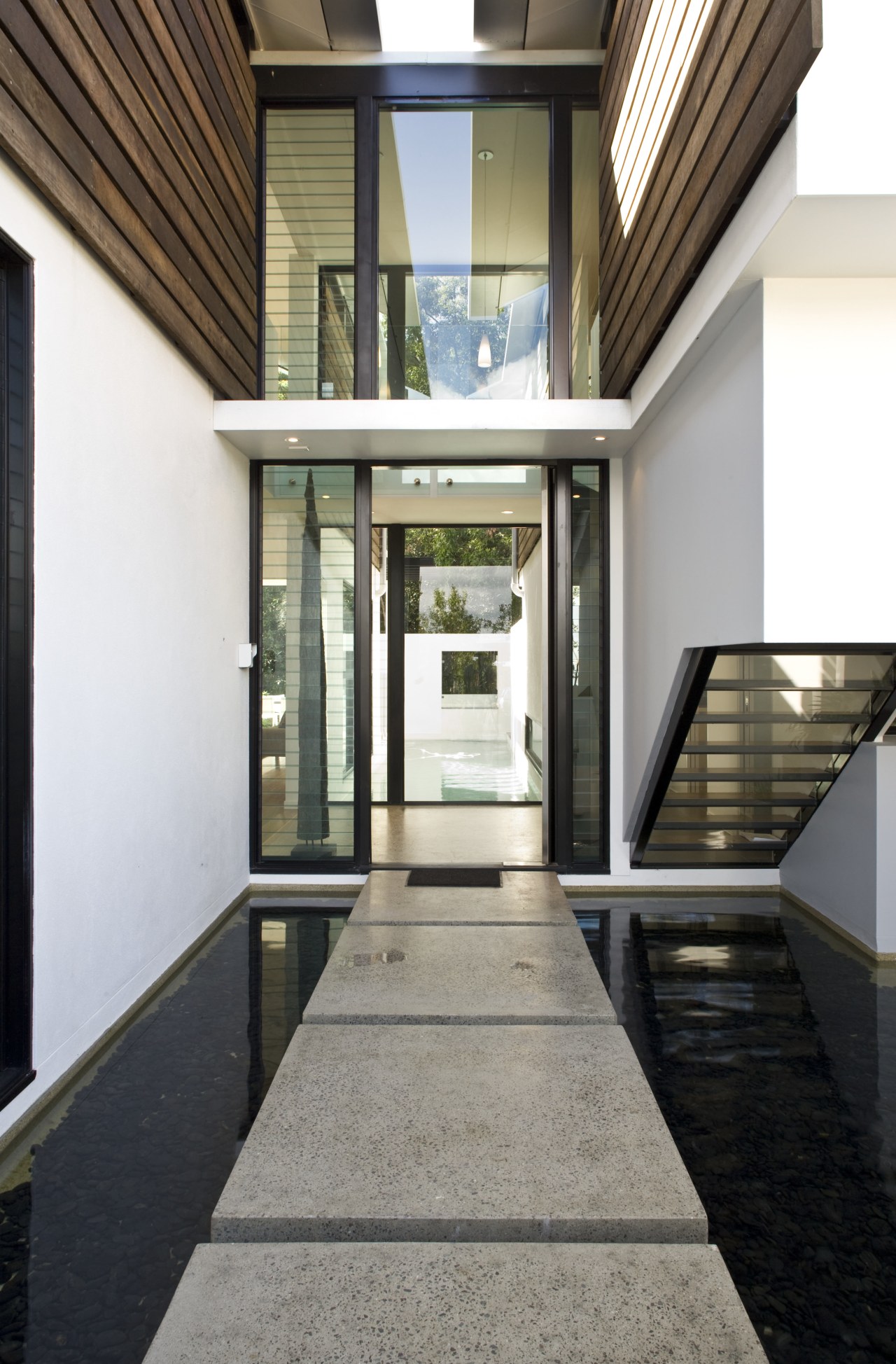 The water feature at the front entrance creates architecture, condominium, daylighting, estate, home, house, interior design, property, real estate, window, white, black