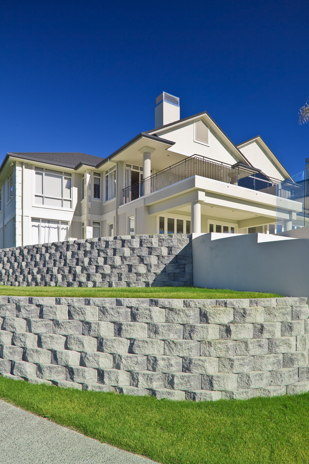 Retaining walls follow the contours of the site. architecture, building, cottage, daytime, elevation, estate, facade, home, house, mansion, property, real estate, residential area, roof, sky, suburb, villa, wall, blue