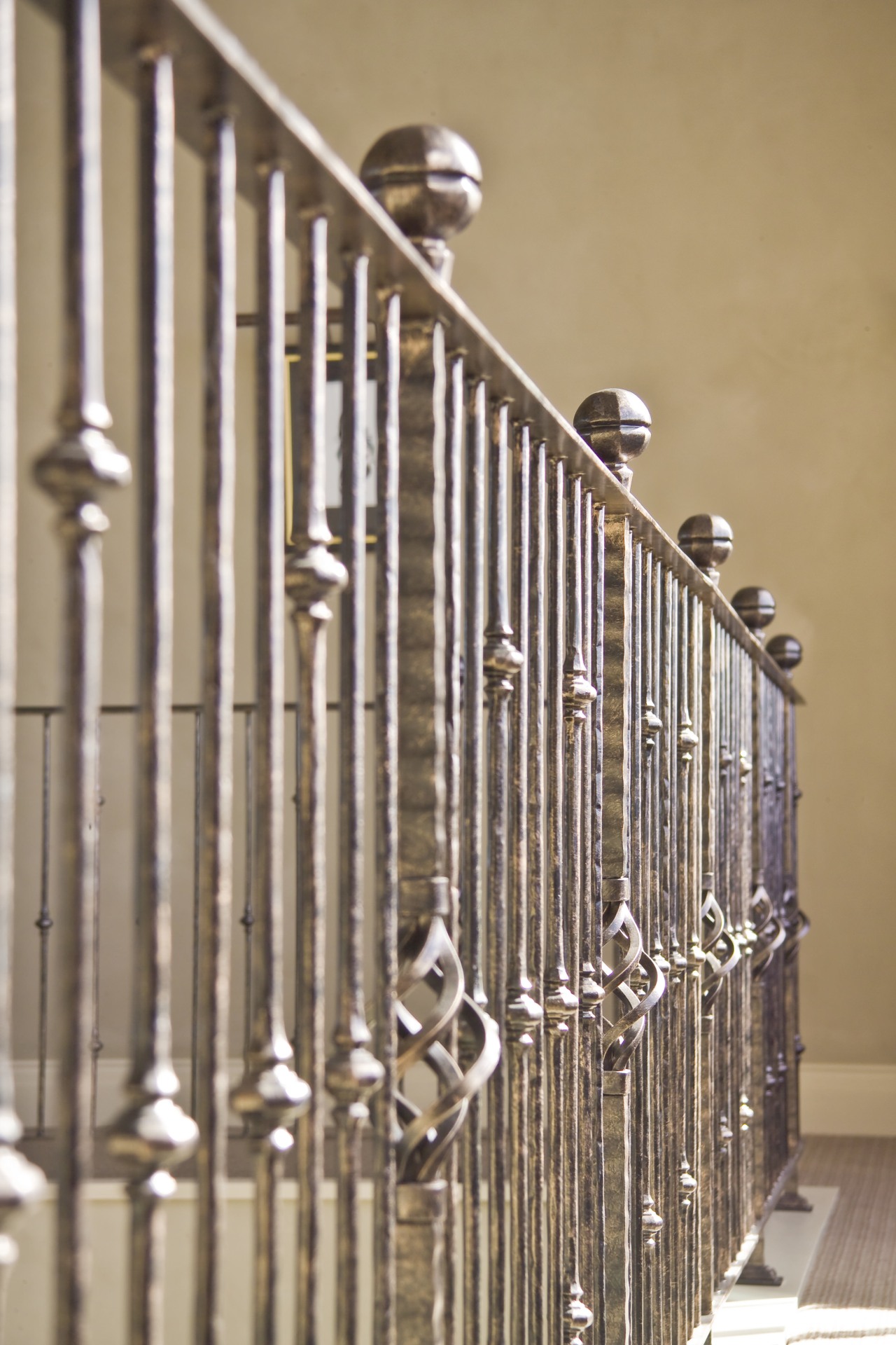 The grand staircase features wrought iron balustrades that baluster, handrail, iron, material, metal, stairs, brown, orange, gray