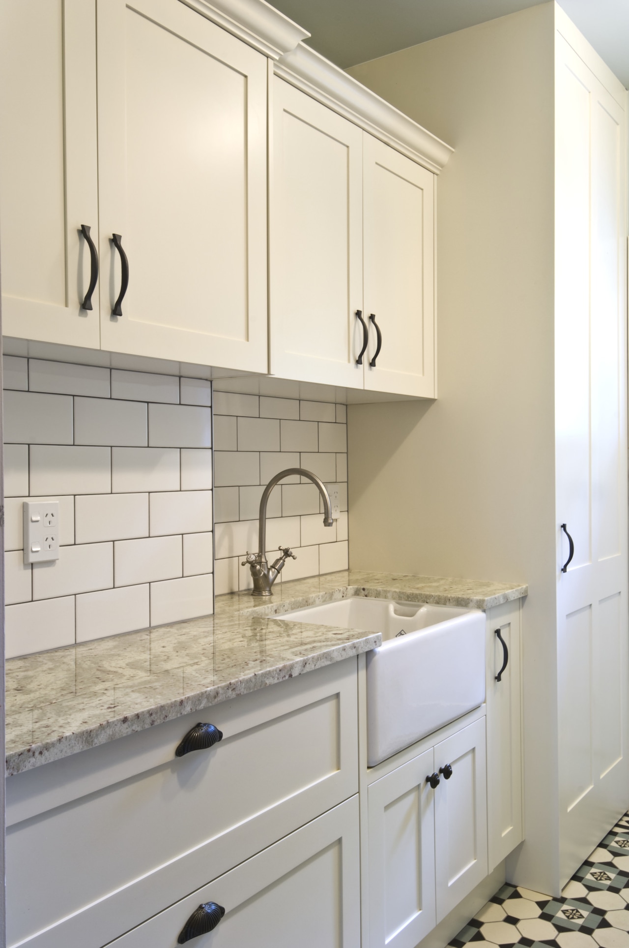 View of laundry, featuring a white butler's sink, bathroom accessory, bathroom cabinet, cabinetry, countertop, cuisine classique, floor, flooring, home, home appliance, kitchen, laundry room, room, sink, tile, wall, gray