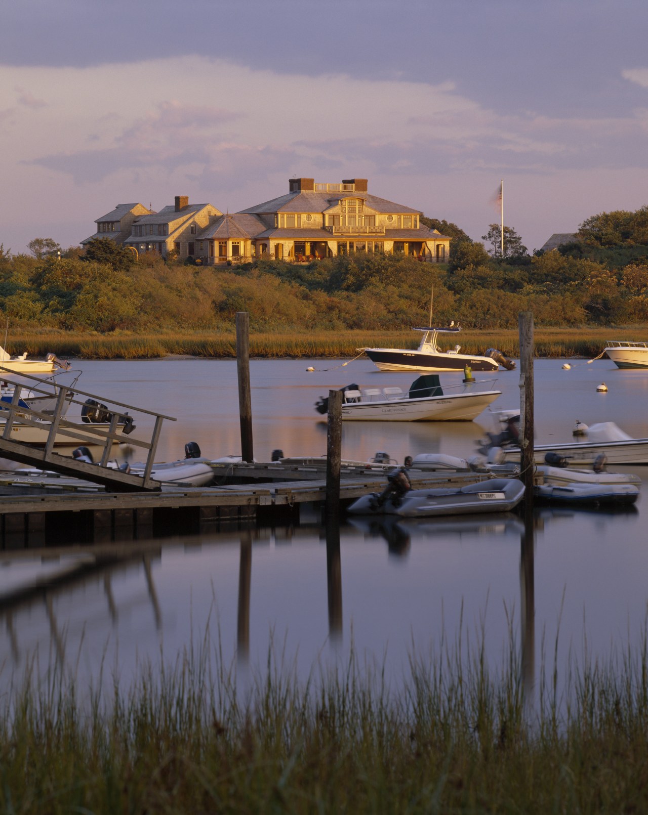 Exterior view of a large cottage with cedar boat, calm, coast, dawn, dock, dusk, evening, harbor, inlet, lake, loch, marina, morning, reflection, river, sea, sky, sunset, water, waterway, purple, brown