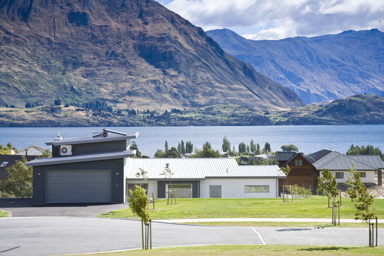 Exterior view of a home which features solar alps, cottage, elevation, estate, fjord, highland, home, house, lake, landscape, mountain, mountain range, property, real estate, residential area, roof, sky, suburb, tree, white