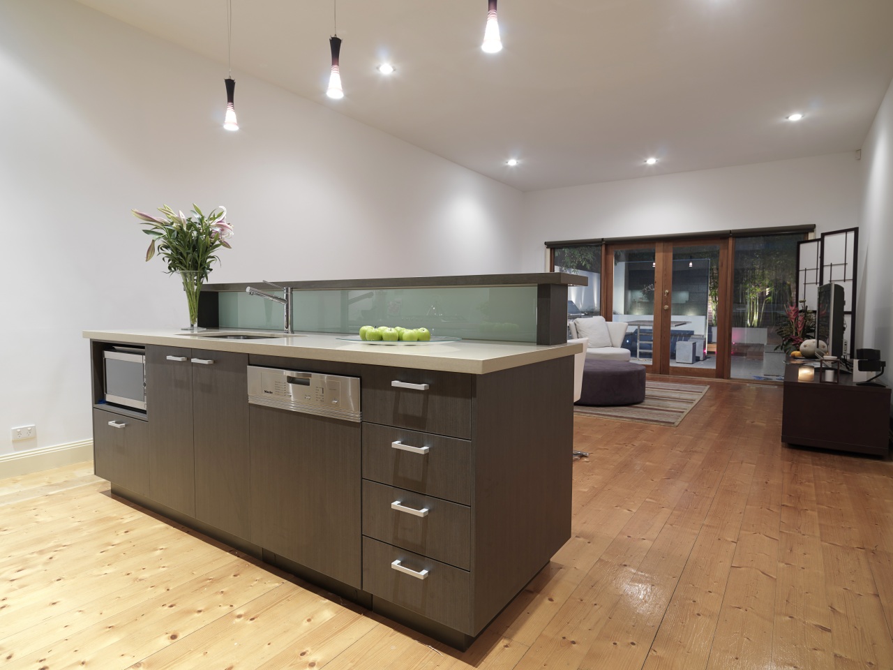 View of a kitchen featuring island, dark brown cabinetry, countertop, floor, flooring, hardwood, interior design, kitchen, real estate, room, gray, brown