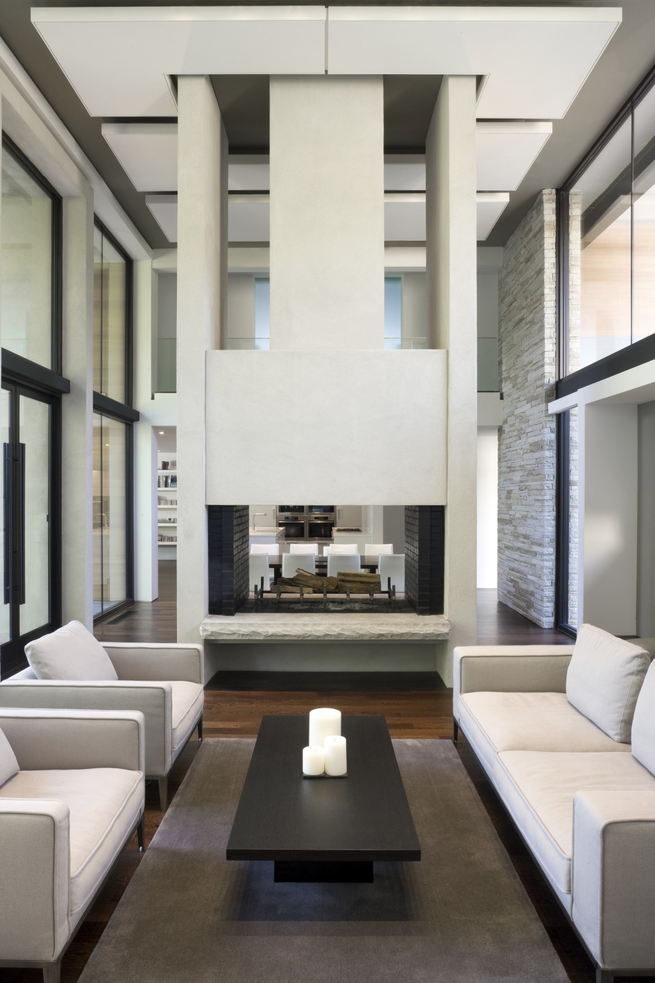 View of living area featuring double story fireplace, architecture, ceiling, floor, furniture, house, interior design, living room, table, white, gray