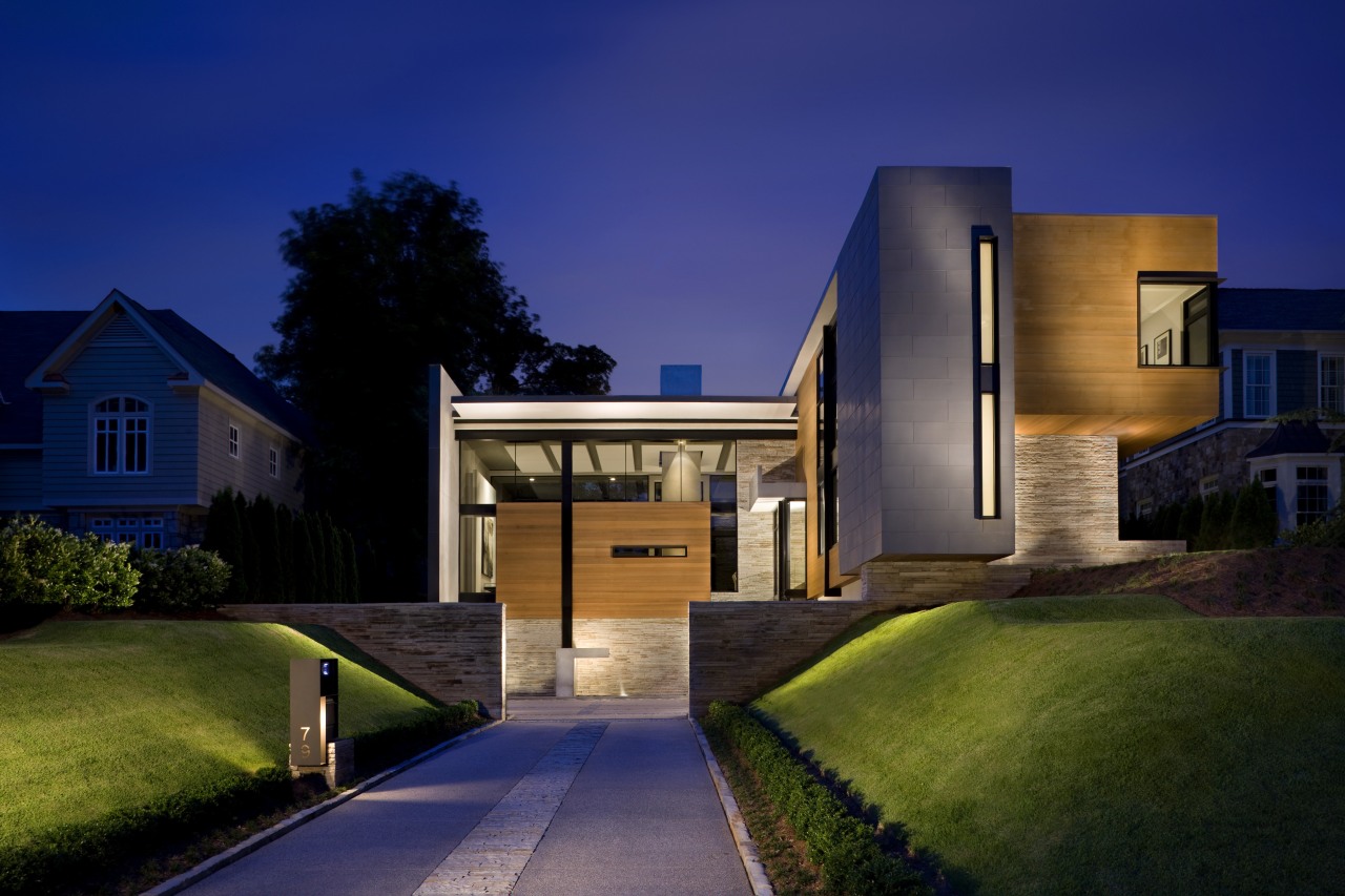 View of the exterior featuring a range of architecture, building, elevation, estate, evening, facade, home, house, landscape lighting, lighting, night, property, real estate, residential area, sky, suburb, sunlight, blue