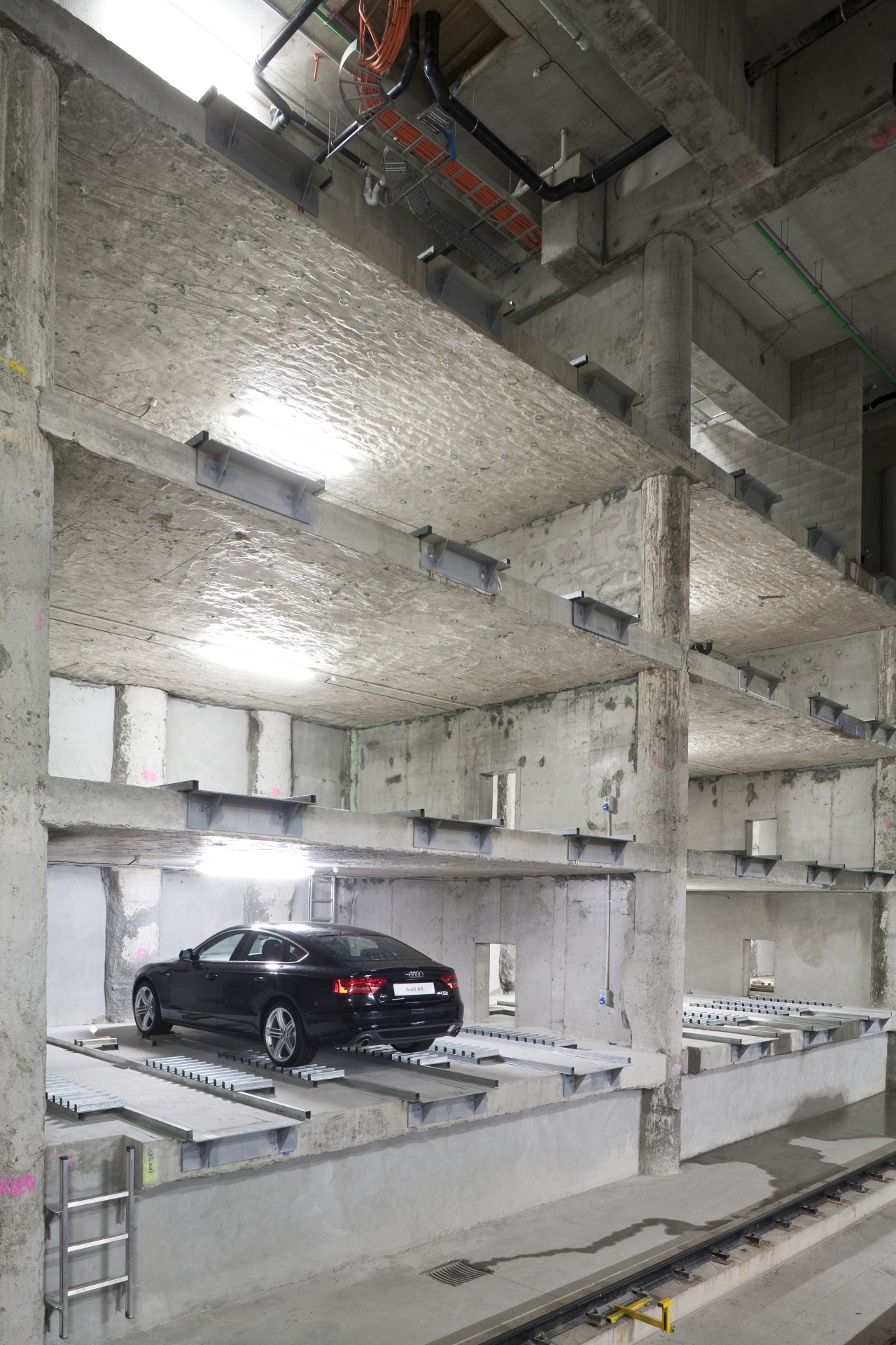 View of the space-saving car-stacking parking system at building, car, wall, gray