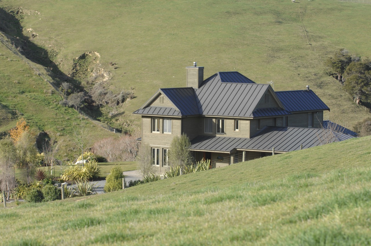 Exterior view of a farm house built by cottage, estate, farm, farmhouse, field, grass, grassland, highland, hill, home, house, hut, land lot, landscape, meadow, mountain, pasture, property, real estate, rural area, sky, tree, village, yellow