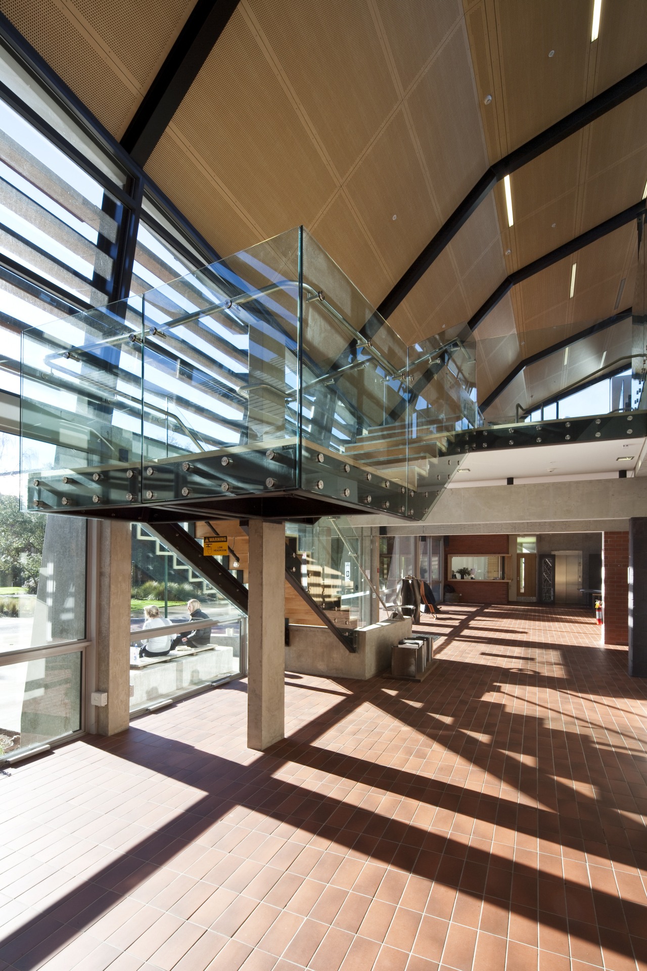 Interior close-up of the large stairway that joins architecture, building, ceiling, daylighting, glass, lobby, structure, brown