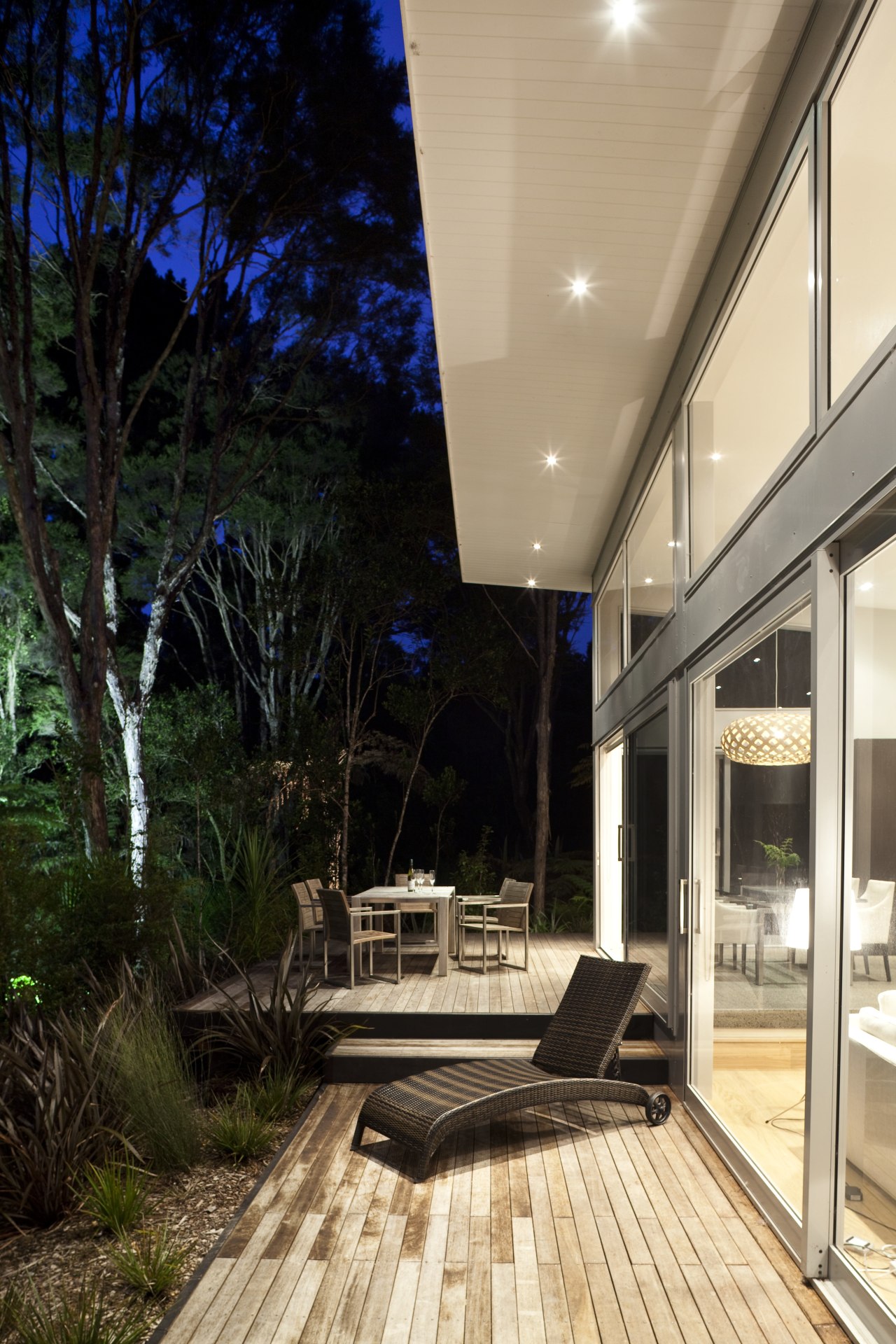 Nighttime shot of contemporary home surrounded by trees. architecture, daylighting, deck, home, house, interior design, outdoor structure, patio, real estate, black, orange