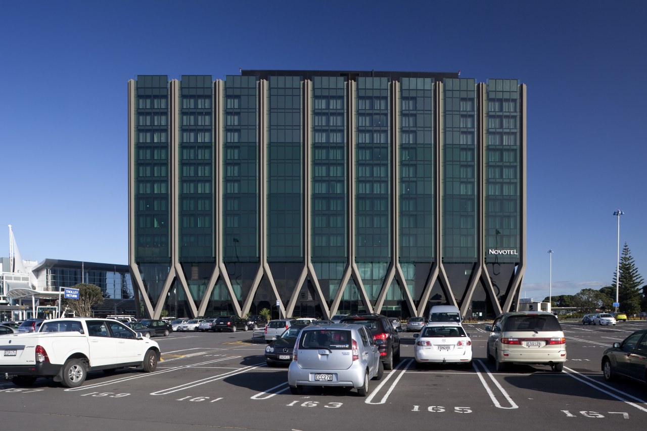 View of the Novotel Auckland Airport in Auckland architecture, building, car, city, commercial building, condominium, corporate headquarters, daytime, facade, headquarters, infrastructure, landmark, luxury vehicle, metropolis, metropolitan area, mixed use, parking, parking lot, sky, tower block, urban area, teal