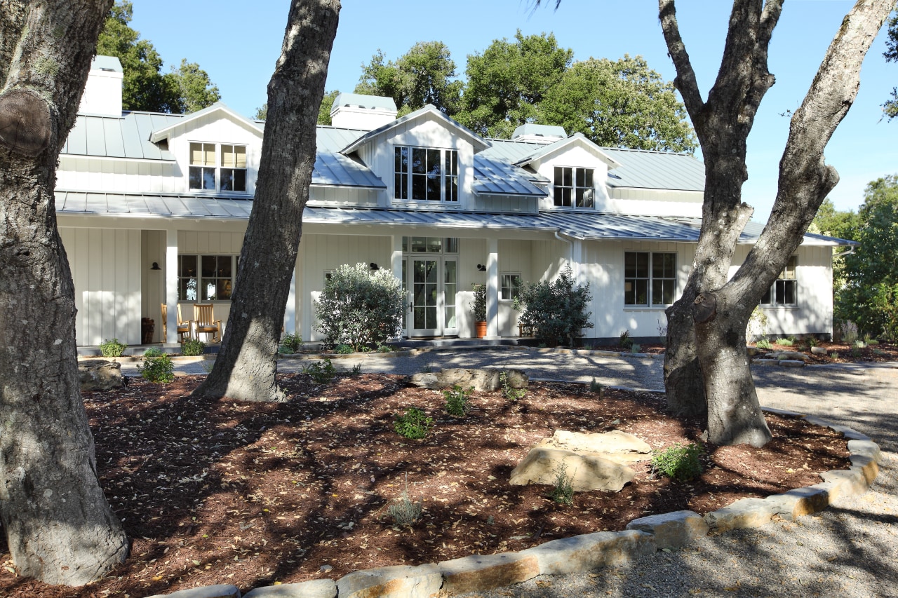 View of exterior with trees in foreground. cottage, estate, home, house, outdoor structure, plant, property, real estate, residential area, tree, yard, black