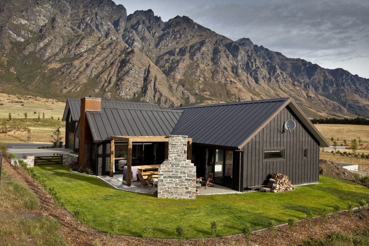 Exterior view of house with dark walls and cottage, elevation, farmhouse, home, house, hut, landscape, log cabin, mountain, mountain range, property, real estate, roof, siding, brown, gray