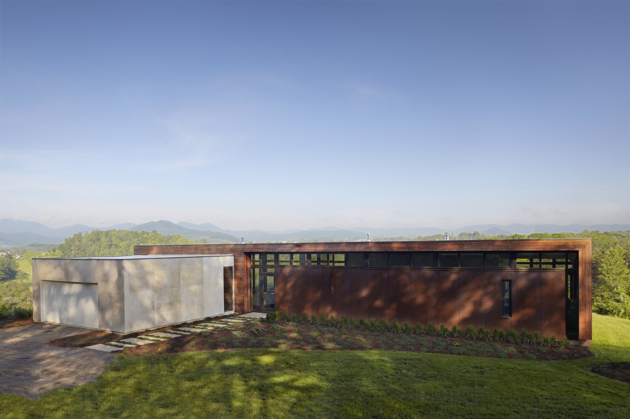 Exterior of house with rusted corten steel. Sustainable architecture, cloud, estate, grass, home, horizon, house, land lot, landscape, property, real estate, rural area, sky, sunlight, teal