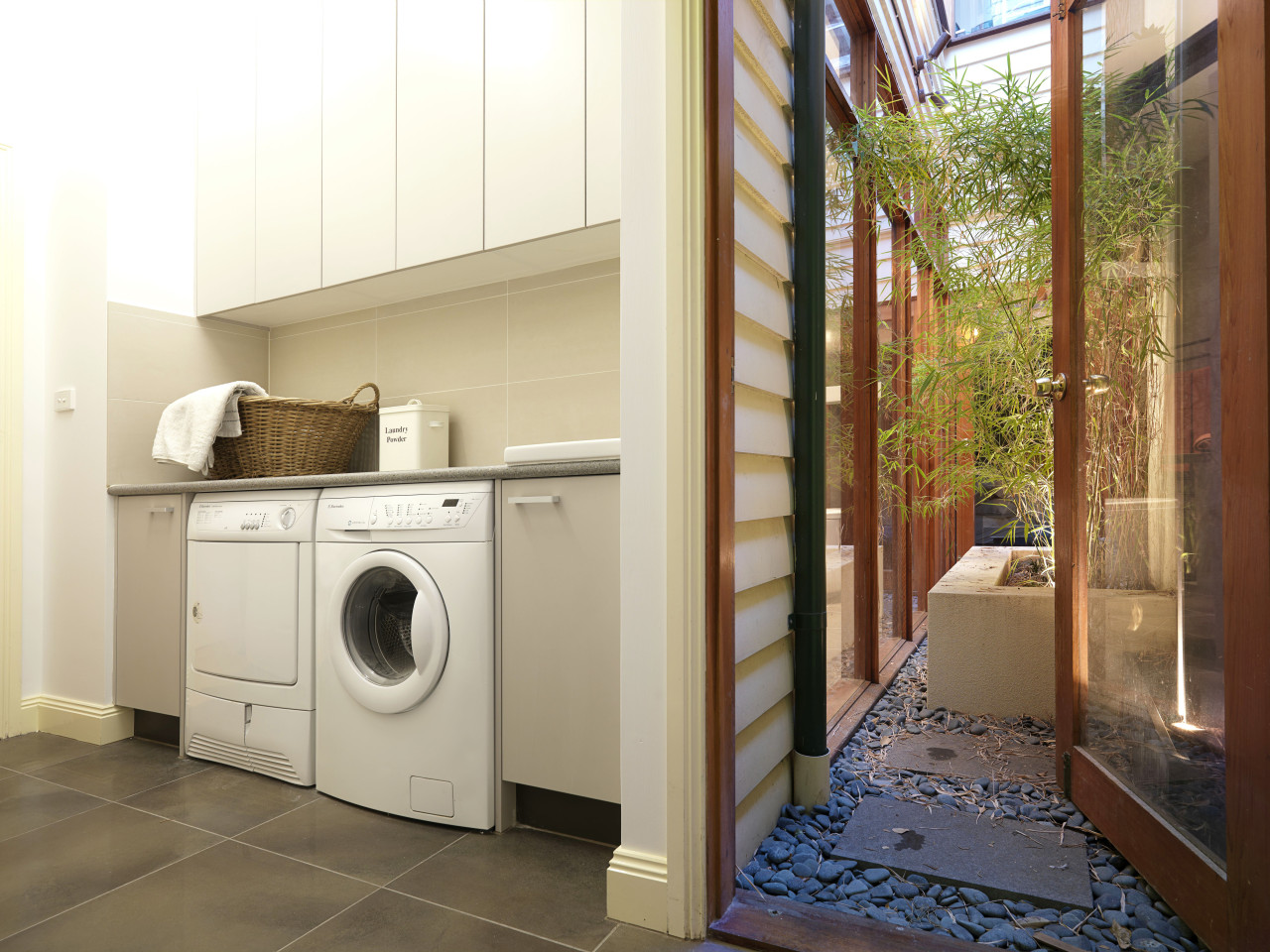 Laundry with grey tiled floor and white cabinets. home, home appliance, laundry, laundry room, major appliance, property, real estate, room, washing machine, white, brown