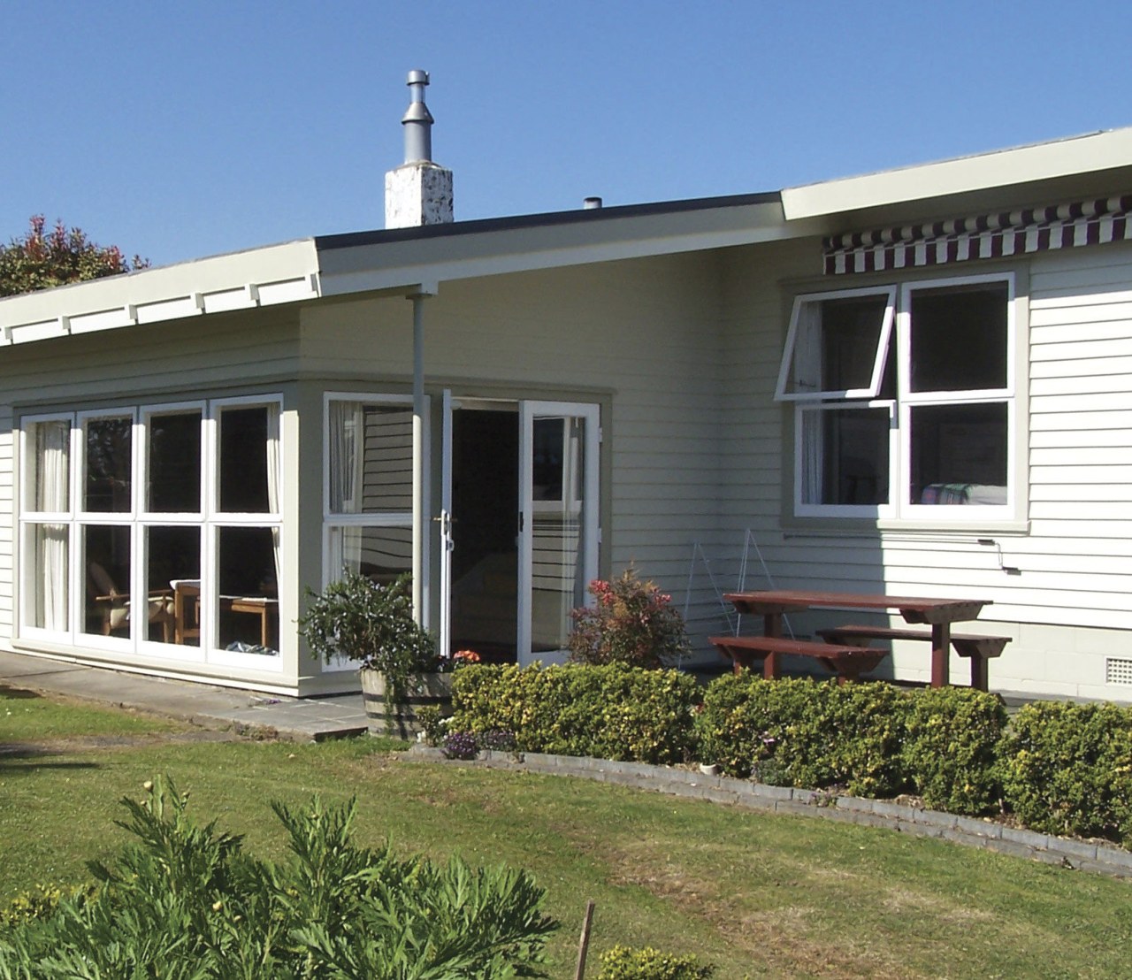 View of exterior with white cladding and lawn. cottage, estate, facade, farmhouse, home, house, porch, property, real estate, siding, window