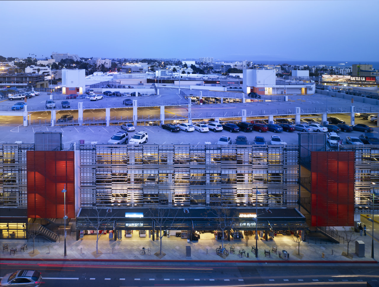 View of parking building at dusk. architecture, building, city, cityscape, condominium, daytime, evening, metropolis, metropolitan area, mixed use, port, real estate, reflection, residential area, sky, structure, suburb, urban area, water, teal, blue