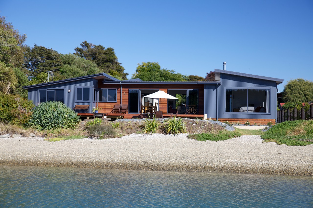 Nestled among the trees on the shoreline at cottage, estate, facade, home, house, property, real estate, sky, villa, water, teal