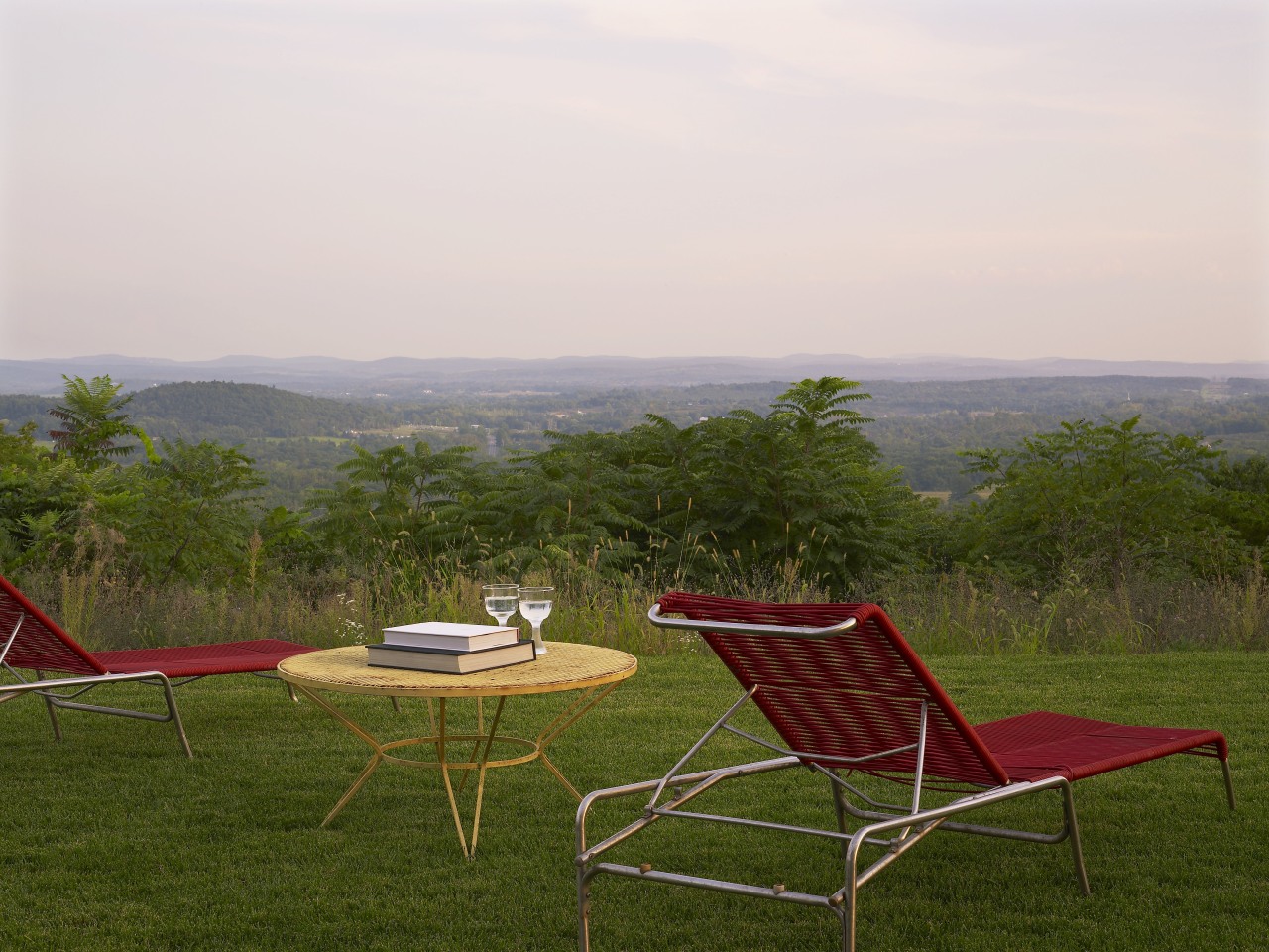 Sitting high on a natural plateau, this house chair, field, furniture, grass, grassland, house, landscape, leisure, meadow, outdoor furniture, plain, plant, rural area, sky, sunlounger, table, tree, brown, white