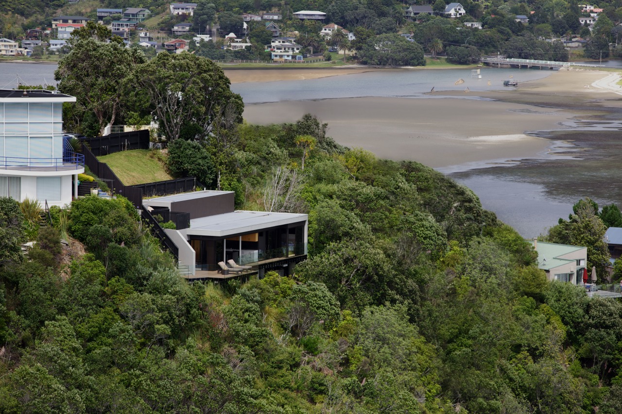 Hidden from the street above, the holiday home home, house, property, real estate, residential area, suburb, tree, water, brown, gray