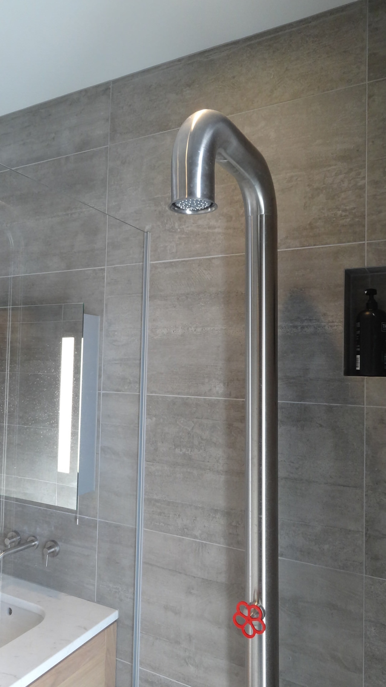 A shower with chunky red handle mixer provides plumbing fixture, shower, tap, gray