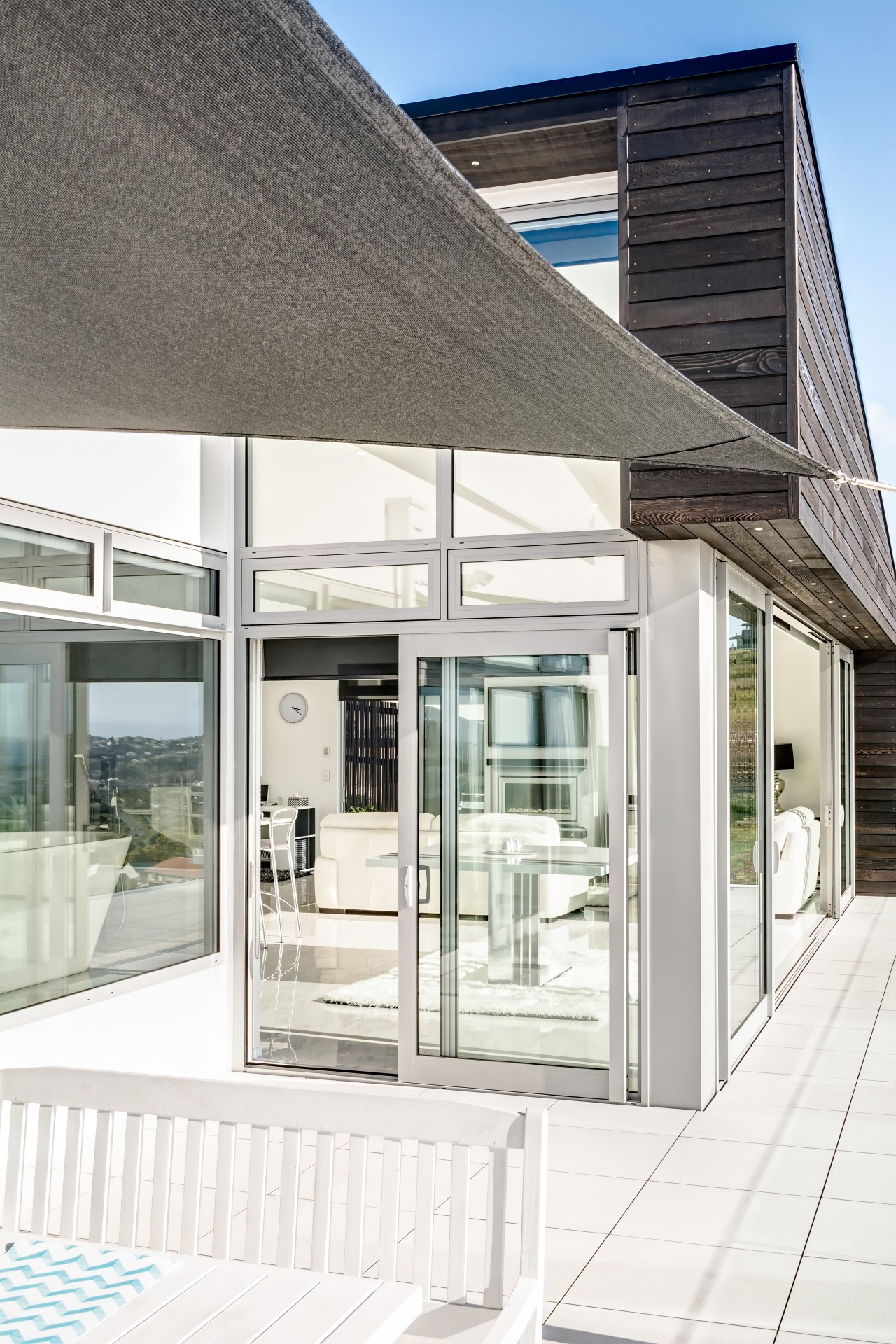 A sail shade shelters the outdoor dining area architecture, building, daylighting, facade, glass, house, window, white