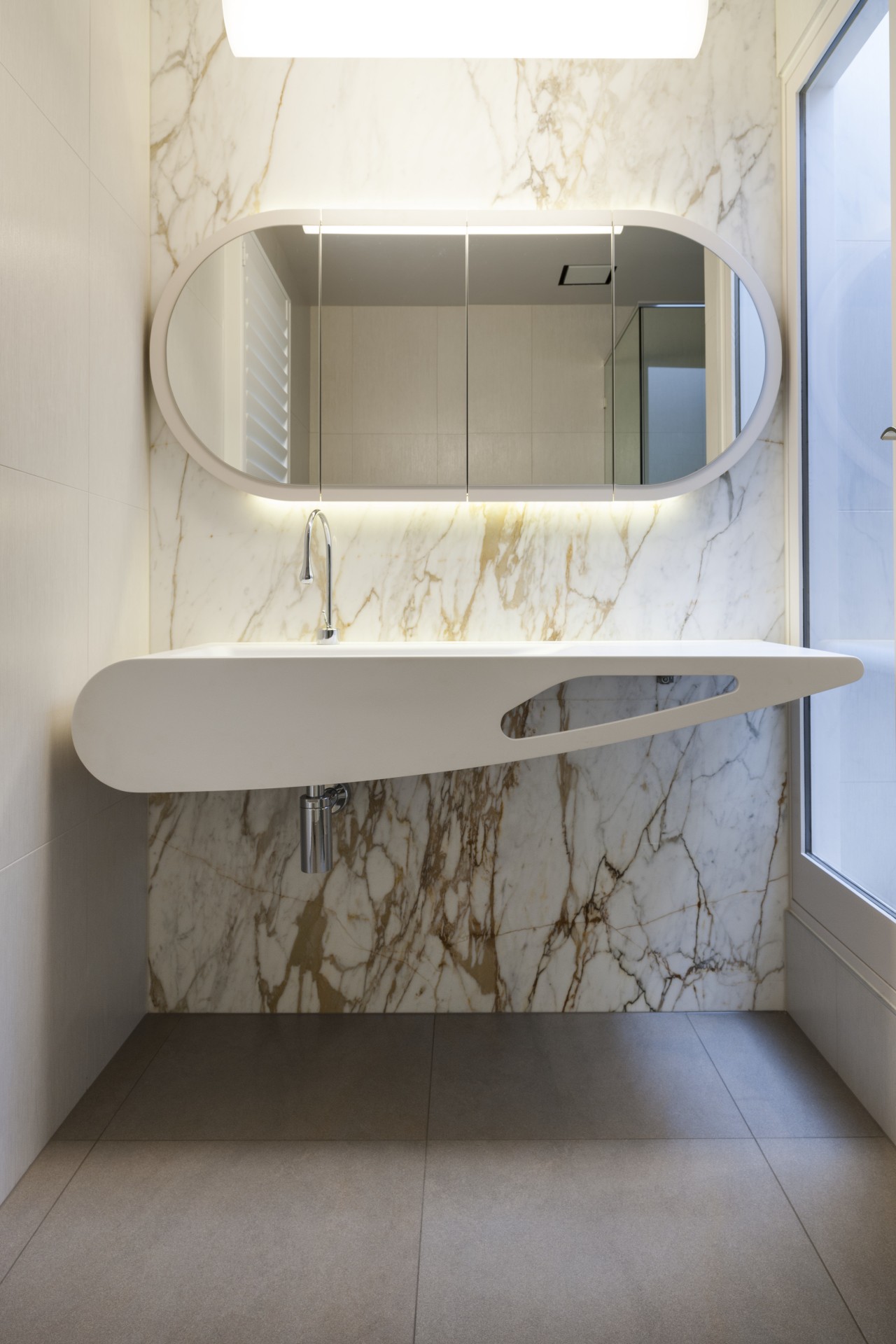 In this design, a richly veined marble feature architecture, bathroom, bathroom accessory, bathroom cabinet, floor, furniture, interior design, product, product design, shelf, sink, tap, tile, wall, gray, white