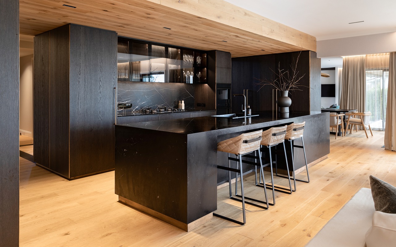 The black kitchen is contrasted with a wood 