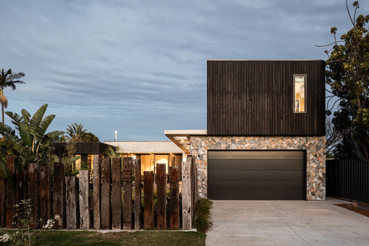 A garage, flanked in natural stone and black 