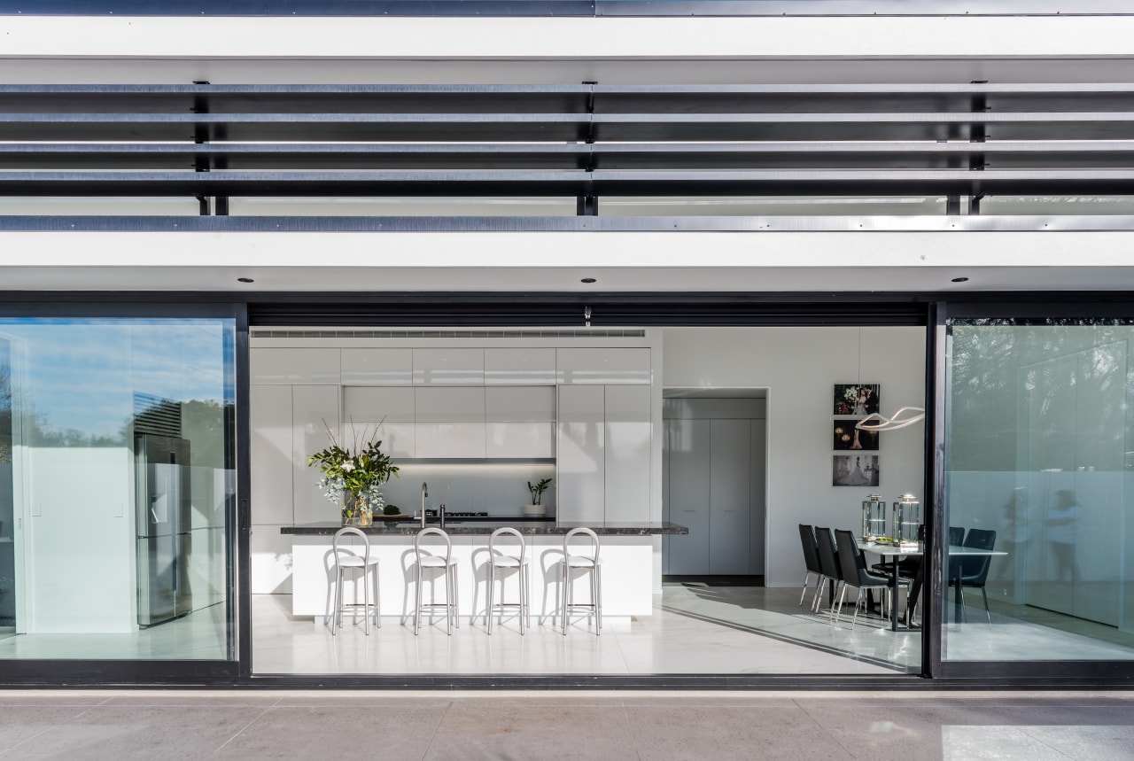 With handleless cabinetry closed, this pristine white entertainer’s door, glass, house, interior design, window, gray