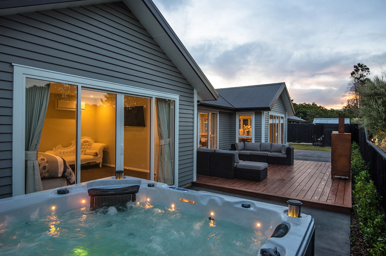 Spa area and evening light on NZ weatherboard backyard, cottage, estate, home, house, outdoor structure, property, real estate, siding, swimming pool, window, black