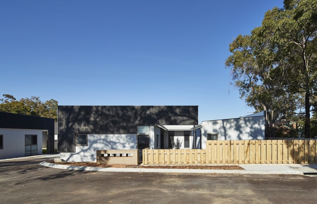 The tree line rises up above the development architecture, building, cottage, facade, home, house, property, real estate, residential area, teal