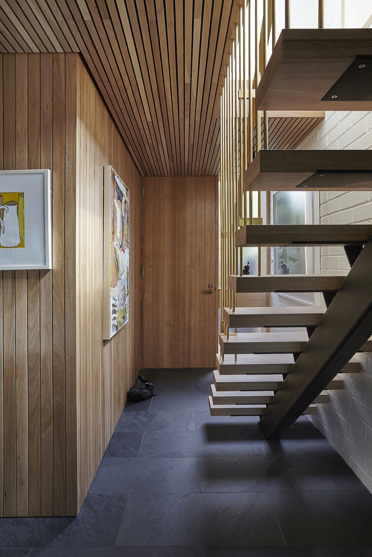 The architects used dark tiles to set the architecture, ceiling, daylighting, floor, flooring, house, interior design, lobby, stairs, wood, black, brown