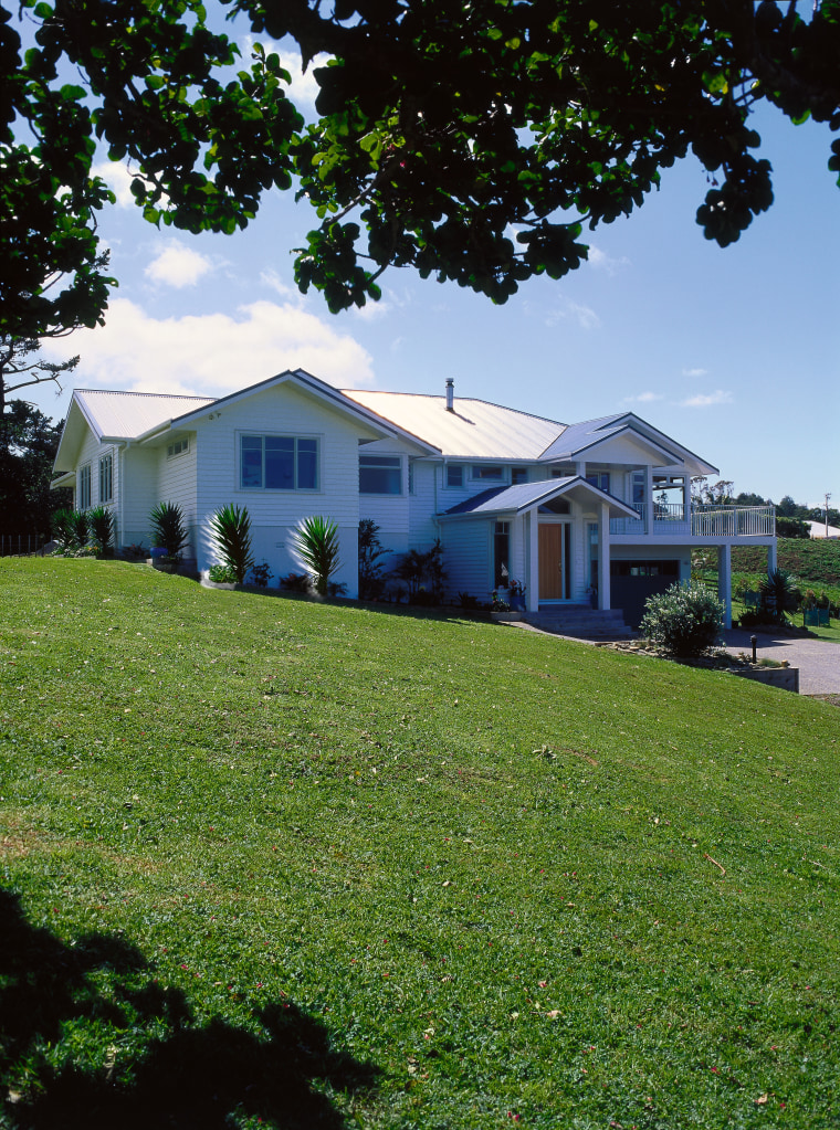 A photograph of a house built on a architecture, backyard, cottage, estate, facade, farmhouse, grass, home, house, land lot, landscape, lawn, neighbourhood, plant, plantation, property, real estate, residential area, rural area, siding, sky, suburb, tree, yard, green