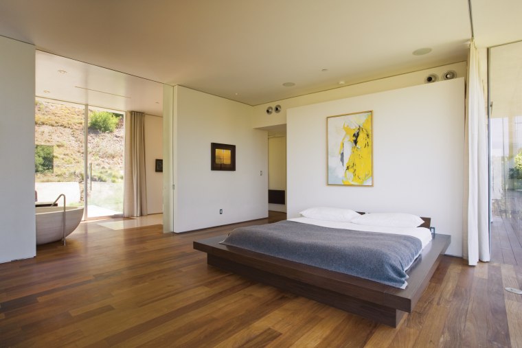 A view of this master bedroom featuring brazilian architecture, bed, bed frame, bedroom, ceiling, estate, floor, flooring, hardwood, house, interior design, laminate flooring, property, real estate, room, wood, wood flooring, gray, brown
