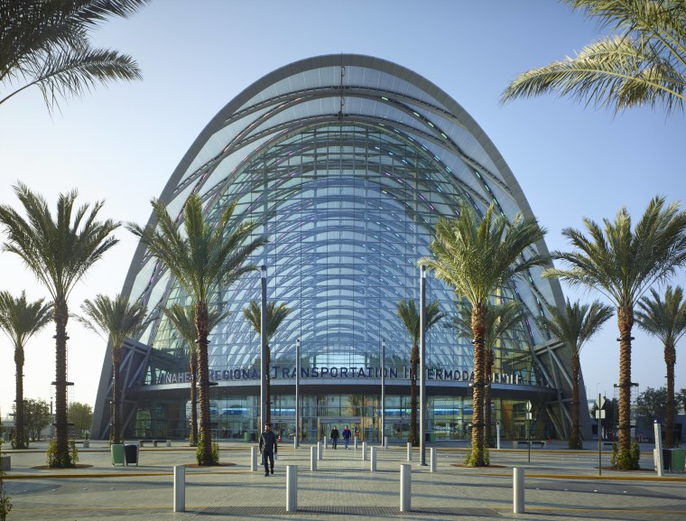 The new ARTIC transit hub in Anaheim is architecture, arecales, building, city, condominium, corporate headquarters, hotel, metropolitan area, mixed use, palm tree, plant, sky, tree, teal