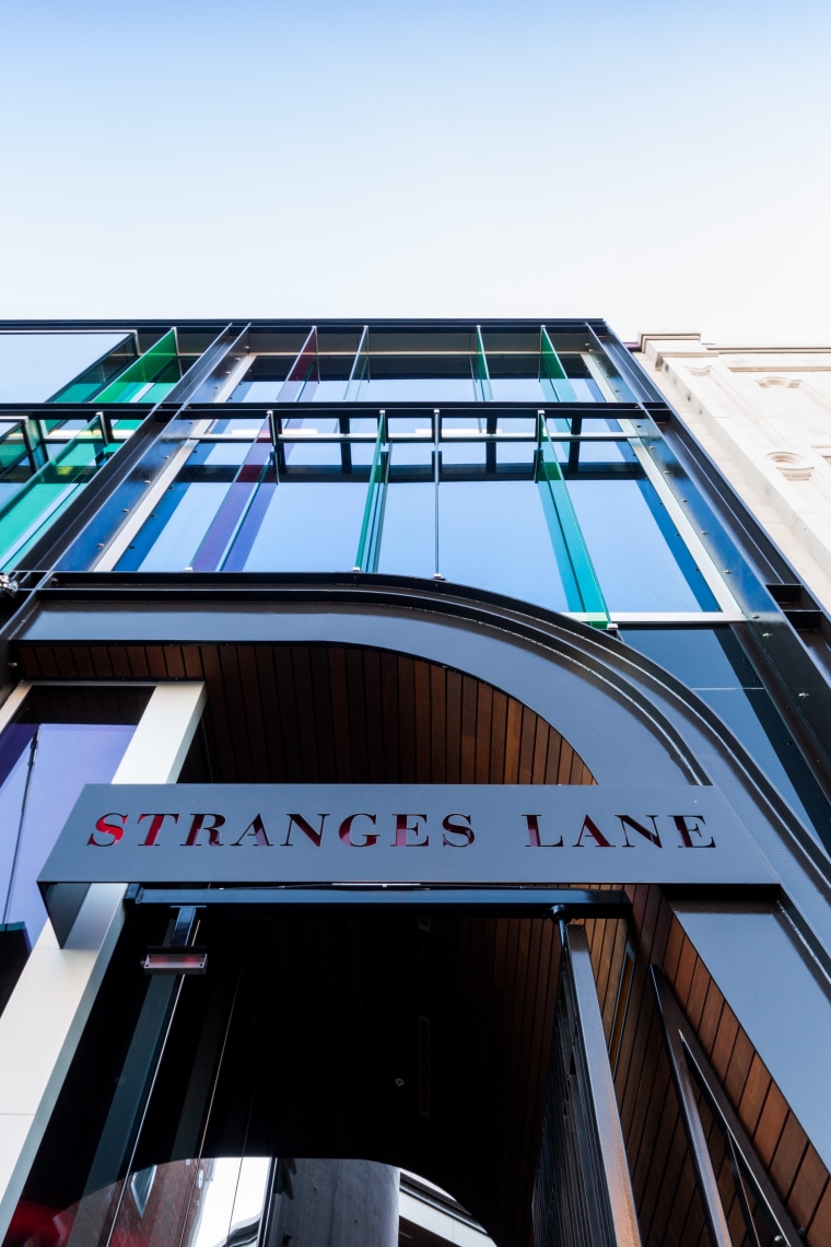 Close-up of STRANGES LANE sign Above:Standing proud architecture, building, commercial building, daylighting, facade, line, metropolitan area, roof, sky, structure, urban area, black, white