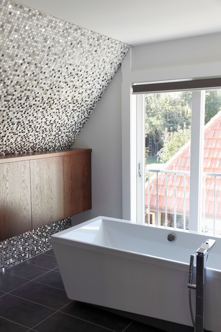 A gabled roof on the house creates sloping architecture, bathroom, bathtub, daylighting, floor, home, house, interior design, plumbing fixture, room, sink, tile, wall, window, white, gray